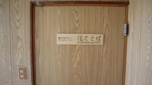 Znak na drewnianych drzwiach z napisem w obiekcie 東神楽大学ゲストハウス w mieście Higashikagura