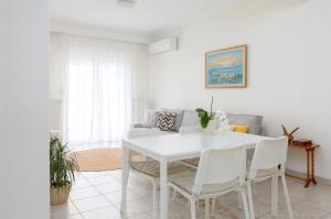 biała jadalnia z białym stołem i krzesłami w obiekcie Mimoza's Sea View Apartment w mieście Palaión Tsiflíkion
