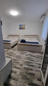 2 łóżka w pokoju z podłogą wyłożoną kafelkami w obiekcie Casa Bianca w mieście Eforie Nord