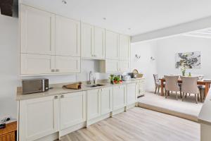 a white kitchen with white cabinets and a table at 10 Clarence Hill - Elegant Town House with outside space in Dartmouth