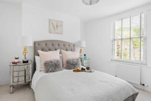 a white bedroom with a large bed with two tables at 10 Clarence Hill - Elegant Town House with outside space in Dartmouth