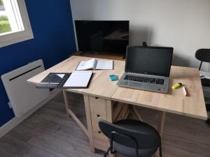 a wooden desk with a laptop computer on it at Charmant studio à côté de la gare in Yvetot