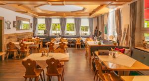 ein Restaurant mit Holztischen und -stühlen und Fenstern in der Unterkunft isarwinkel in Geretsried