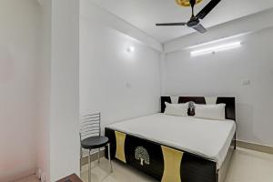 OYO Hotel R Glory في باتنا: غرفة نوم بيضاء بسرير وكرسي