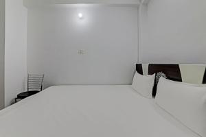 a white bedroom with a large bed and a chair at OYO Hotel R Glory in Patna