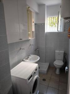 a bathroom with a toilet sink and a washing machine at Apartment 50 meters from the beach in Loutraki