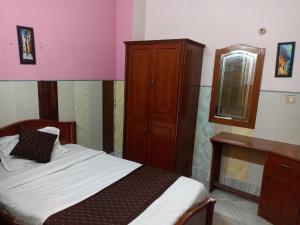 um quarto com uma cama, um armário e um espelho em HOTEL RIZ VARANASI em Varanasi
