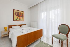 biała sypialnia z łóżkiem i krzesłem w obiekcie Mimoza's Sea View Apartment w mieście Palaión Tsiflíkion
