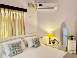um quarto com uma cama branca com almofadas em LUSO Beach Homes Goa em Benaulim