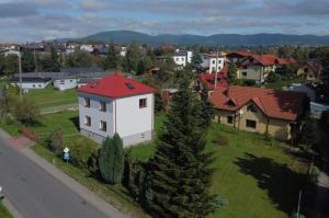 a small white house with a red roof on a green field at Apartament u Jędrusia I in Żywiec