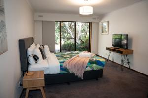 a bedroom with a bed and a desk and a window at Port Bayou House in Port Campbell