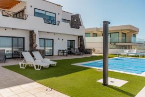 una villa con piscina e sedie a sdraio di Seascape Piscina climatizada aire acondicionado a Corralejo