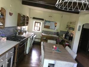 a kitchen with a wooden table and a counter top at Grande maison entre vert et bleu in Saint-Yrieix-la-Montagne