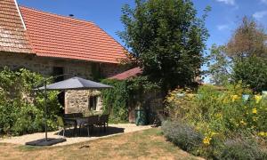 a table and an umbrella in the yard of a house at Grande maison entre vert et bleu in Saint-Yrieix-la-Montagne