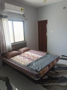 a bed sitting in a room with a window at Matoshree Guesthouse in Akalkot
