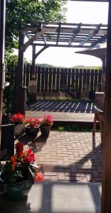 a patio with potted plants and a wooden pergola at Room on the River in Cruden Bay