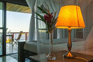 Naara Eco Lodge & Spa في تشيدينغيل: طاولة مع مصباح و مزهرية مع الزهور