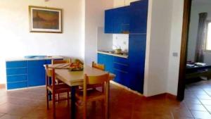 a kitchen with blue cabinets and a table and chairs at Residence Poseidon Villaggio in Isola Capo Rizzuto +16 photos