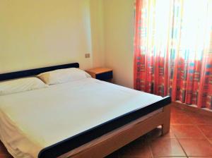 a bedroom with a bed and a window with curtains at Residence Poseidon Villaggio in Isola Capo Rizzuto