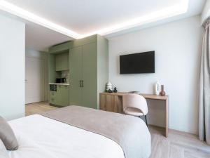 um quarto com uma cama, uma secretária e uma televisão em ASTIKON Xenofontos Suites em Atenas