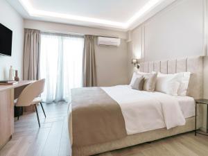 um quarto com uma grande cama branca e uma secretária em ASTIKON Xenofontos Suites em Atenas