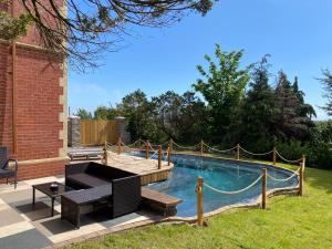 un patio trasero con una piscina con una mesa y un banco en Coastal Escape: 4 bed mansion, en Port Talbot