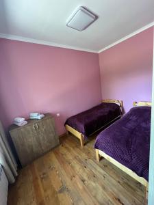 Habitación con 2 camas, paredes de color púrpura y suelo de madera. en Balkonchik GuestHouse, en Dilijan