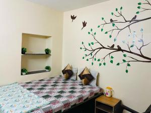 a bedroom with a bed and a tree with birds on the wall at Sun India Guest House in Hāora