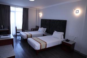 um quarto de hotel com duas camas e uma secretária em Trinity Hotel em Addis Ababa