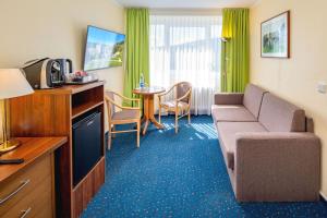 a hotel room with a couch and a table at AHORN Hotel Am Fichtelberg in Kurort Oberwiesenthal