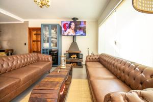 a living room with brown leather couches and a tv at Unalome Pousada in Serra Negra