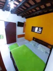 サンタ・マルタにあるAPARTAHOTEL BACANO LOFTの黄色の壁のベッドルーム1室(緑のベッド1台付)