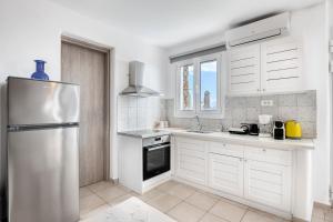 cocina con armarios blancos y nevera de acero inoxidable en Dream Villa Santorini, en Vourvoúlos