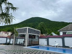 a house with a swimming pool in front of a mountain at Qafqaz Modern Luxryland in Gabala