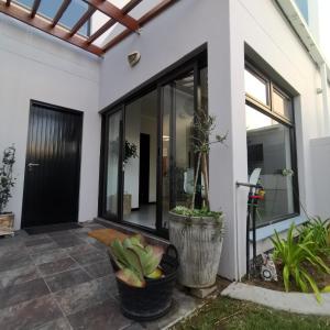 a home with large glass doors and plants at Beachfront Townhouse - MowenOne in Walvis Bay