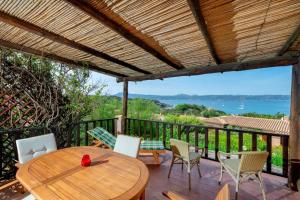 una mesa de madera y sillas en una terraza con vistas en Sea View Mucchi Bianchi, en Baja Sardinia