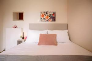 um quarto com uma cama branca e uma almofada rosa em Country House in Agios Leon em Agios Leon