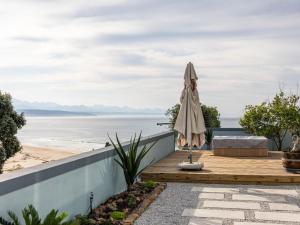Una mujer parada en el borde de una casa con vista a la playa. en Keurbooms Lagoon Villa, en Plettenberg Bay