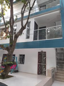 un edificio blanco con un árbol delante en Apartaestudio Cartagena 2P en Cartagena de Indias