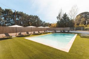 a swimming pool with chairs and umbrellas on a lawn at Soko Hotels-Pont du Gard in Remoulins