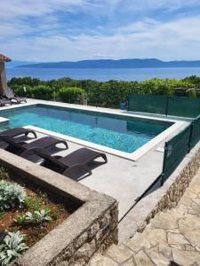 una piscina con sillas y el océano en el fondo en House Olive Bay View, en Drenje