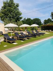a swimming pool with lounge chairs and umbrellas next to a pool at La linea dell'orizzonte in Alberobello