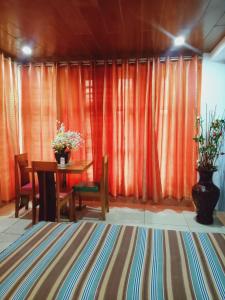 uma sala de jantar com uma mesa e cortinas cor de laranja em CITI HOTEL em Hilongos