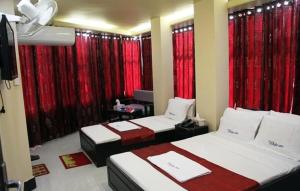 a hotel room with two beds and red curtains at White Inn luxury Residential Hotel in Chittagong
