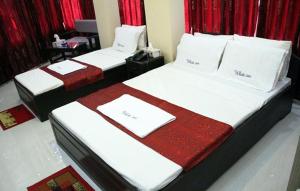 two beds in a hotel room with red curtains at White Inn luxury Residential Hotel in Chittagong