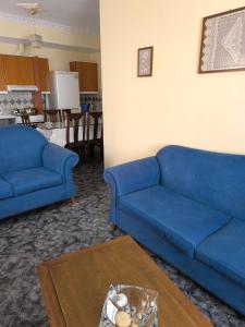 uma sala de estar com dois sofás azuis e uma mesa em Robert House em Samos