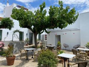 a patio with tables and chairs and a tree at Les Filles (antiga Fonda de la Parra) in Deltebre