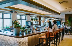 two people sitting at a bar in a restaurant at Hotel Resol Trinity Naha in Naha