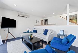 a living room with blue chairs and a tv at Goldfield Holiday Home in Queenstown