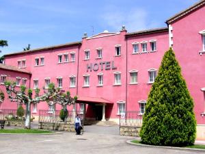 un hotel rosa con una mujer parada frente a él en Hotel San Camilo en Navarrete